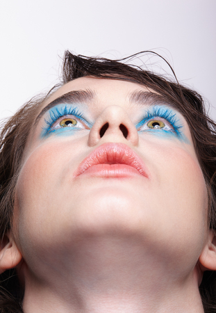 Closeup macro portrait of female face. Woman  with unusual beauty makeup. Girl with perfect skin, green pistachio colour eyes and blue shadows make-up.の写真素材