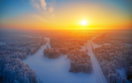 Sun over siberian furest under the snow at morning time. Siberian rural winter sunrise landscape with birch trees covered with hoarfrost. Aerial shot from drone.の写真素材