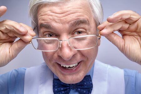 Close up portrait of senior businessman clerk looking ironically at the camera. Adult middle-aged...