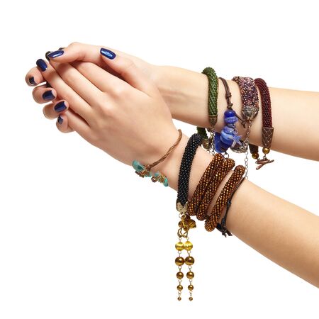 Female hands with handmaid bijouterie bracelets isolated on white background. Nails with blue manicure and wrists are with bijouterie bracelets.の写真素材
