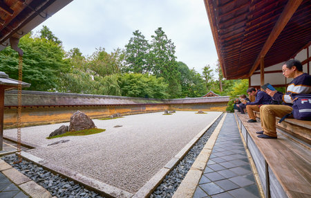 Peoples on the veranda of the Hojo, the head priest's former residence contemplate the Zen garden - the dry landscape (karesansui ) rock garden. Ryoan-ji temple. Kyoto. Japanのeditorial素材