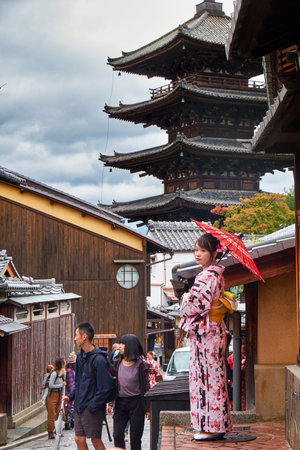 KYOTO, JAPAN - OCTOBER 18, 2019:  The woman in Japanese kimono on the cobbled alley with traditional Japanese style buildings with the Hokan-ji Temple (Yasaka Pagoda) on the background. Kyoto. Japanのeditorial素材
