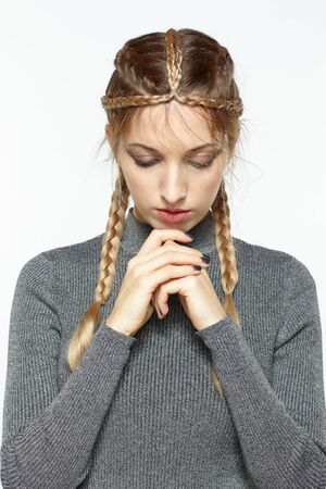 Portrait of beautiful young dark blonde woman. Female with creative braid hairdo on gray background....