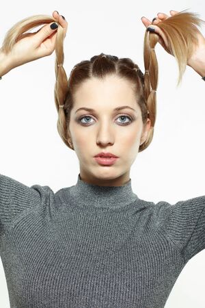 Portrait of beautiful young dark blonde woman. Female with creative braid hairdo on gray background....