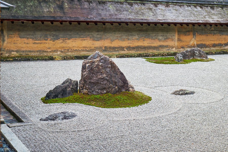 The view of separate groups of boulders surrounded by the waves of white gravel in the famous stone Zen garden of Ryoan-ji temple. Kyoto. Japanのeditorial素材