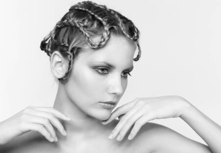 Black and white portrait in high key tone of beautiful young dark blonde woman with creative braid hairdo  touching her chinの写真素材