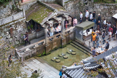 Kyoto, Japan - November 23, 2007: Visitors at the Otowa waterfall catching the water of one of the three separate streams for health, longevity, and success. Kiyomizu-dera temple. Kyoto. Japanのeditorial素材