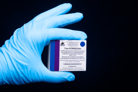 Moscow, Russia - February 10, 2021: Hand in medical glove holding packaging box with vaccine with Sputnik V vaccine Gam-COVID-Vac. Vaccine was developed by the Gamaleya Research Institute of Epidemiology and Microbiology.のeditorial素材