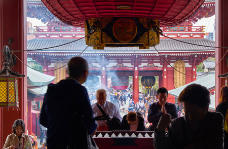Tokyo, Japan - October 24, 2019: People praying at the entrance to the main hall in front of offering box (saisen) under the great red lantern (akachochin). Sensoji Kannon temple in Asakusa.のeditorial素材