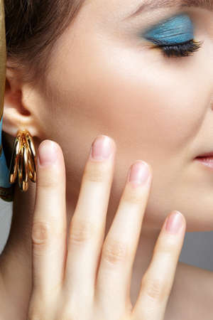 Portrait of young woman on gray background. Female with closed eyes posing with hand near face....
