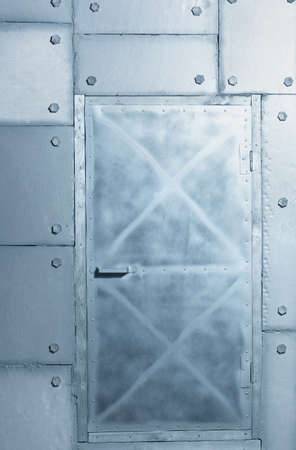 Background of silvery wall and door made of polyethylene foam sheets imitating metal with rivets. Iron wall background.の写真素材