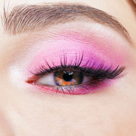 Closeup macro shot of human female eye. Woman with natural evening vogue face beauty makeup. Girl with perfect skin and pink eyes shadows.の写真素材