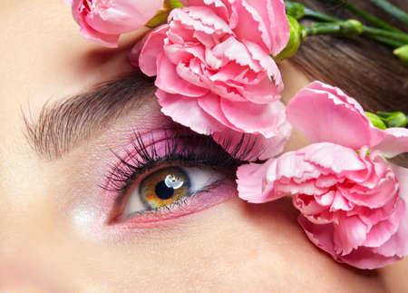 Closeup macro shot of human female eye. Woman with natural eyes beauty makeup. Pink carnation...