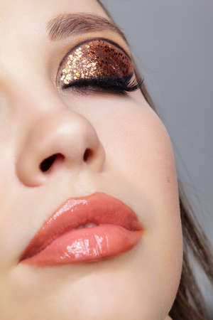 Close-up shot of female face with vogue golden shining eyes makeup. Eyes closed.