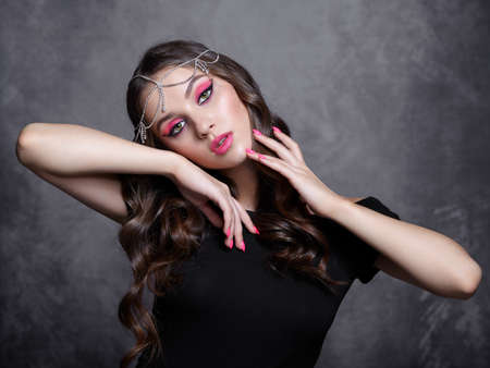Beauty portrait of a young woman on gray background. Brunette girl with an oriental appearance with...