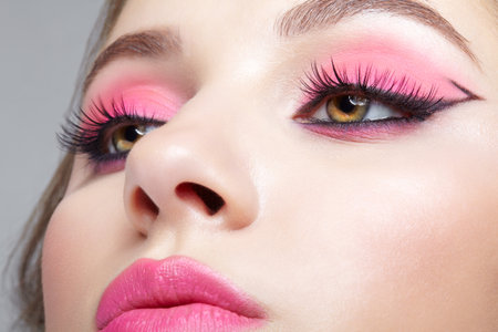 Close up macro shot of human female face. Woman with an oriental appearance and pink eyes and lips...