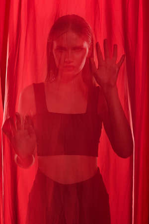Portrait of young woman wrapped in red half transparent cloth.