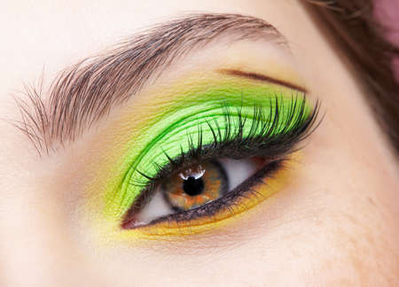 Close up macro shot of human female eye. Woman with vogue face beauty makeup. Girl with green and yellow eyes shadows.の写真素材