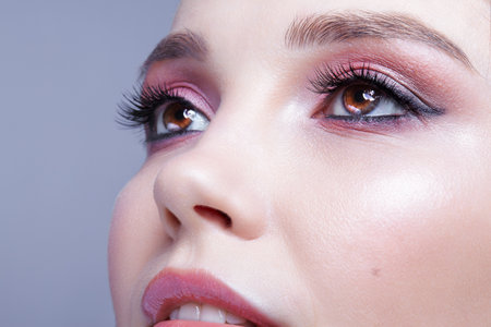Close up shot of human woman face. Female with natural face and eyes beauty makeup with pink smoky eyes eye shadowsの写真素材