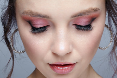 Close up shot of human woman face. Female with natural face and eyes beauty makeup with pink smoky eyes shadows. eyes closed.の写真素材
