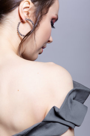 Young woman with unzipped zipper on the dress. view from the back. Bunette female rear view with hair knot and earrings in the ears.の写真素材