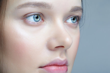Close up macro shot of human female face. Woman with blue eyes and natural face beauty makeup.の写真素材