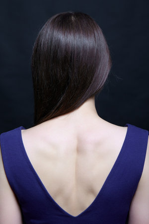 Young brunette woman in blue dress. Female view from the back side.