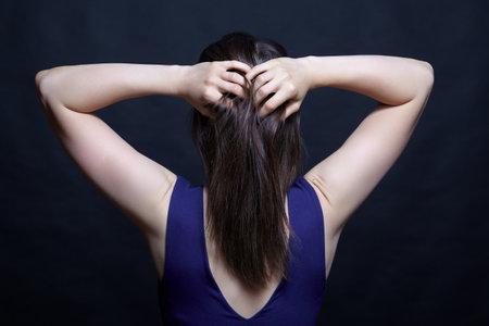 Young brunette woman in blue dress. Female view from the back side. Hamds on head.の写真素材