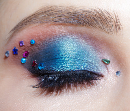Closeup macro shot of closed human female eye with blue eye shadow make up and rhinestones. Woman with natural evening vogue face beauty makeup.の写真素材