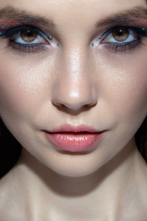 Close up shot of human woman face. Female with natural face and eyes beauty makeup with blue eye shadow make up and rhinestones.の写真素材