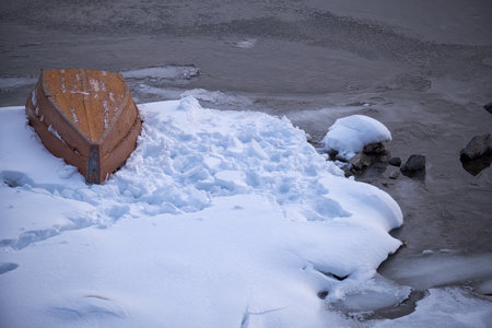 Altai winter landscape with the river Biya. Water runs among the snow-covered banks. An overturned boat lies on the ice near the bank.の写真素材