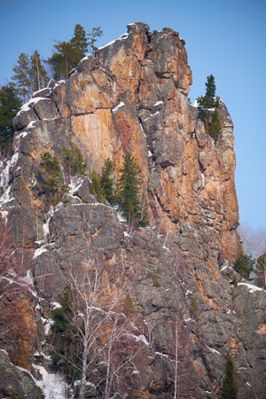 Rocky mountain covered with forest and snow against the blue sky. Altai.の写真素材