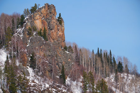 Rocky mountain covered with forest and snow against the blue sky. Altai.の写真素材