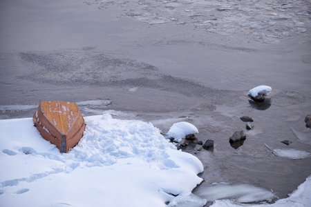 Altai winter landscape with the river Biya. Water runs among the snow-covered banks. An overturned boat lies on the ice near the bank.の写真素材