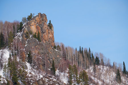Rocky mountain covered with forest and snow against the blue sky. Altai.の写真素材