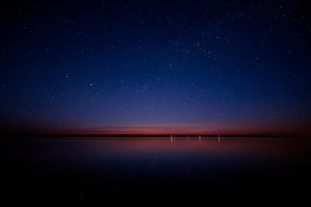 Night sky and the stars reflected in waterの写真素材