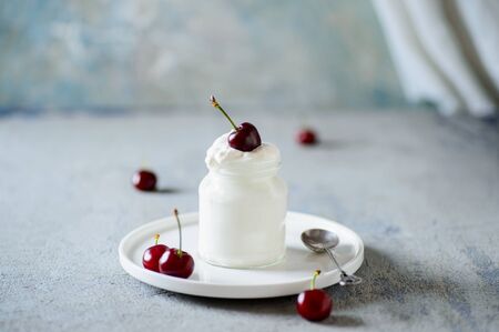 Red cherries dipped in whipped cream or yoghurtの写真素材