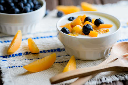 Yogurt with fresh blueberries, corn flakes and apricots on a textural brown surfaceの写真素材