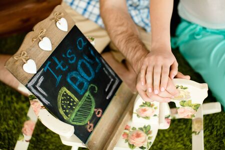 Man hugging his pregnant wife and holding a blackboard on grey backgroundの写真素材