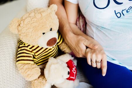 Romantic moment. Faceless photo of a couple sitting on the bench and holding hands.の写真素材