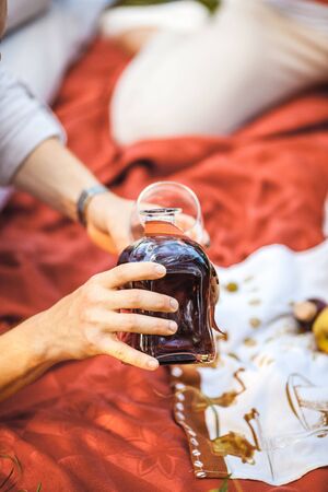 Man pours red wine in glass at the picnicの写真素材