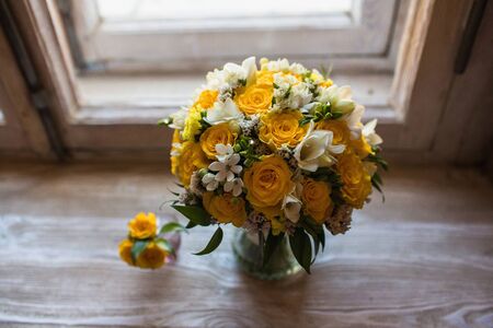 Beautiful wedding bouquet and groom's boutonniere on the windowsill backgroundの写真素材