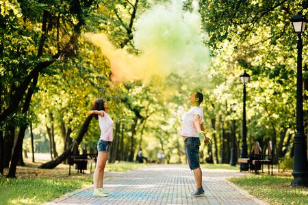 Young and beautiful, hipster couple funny playing in the park on holi color festival with colour paint powder. Dressed in white T-shirts and denim shorts.の写真素材