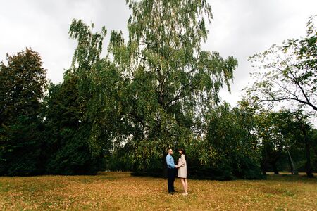 Pregnant beautiful woman and her handsome husband lovely relaxing, hugging on nature and have picnic in autumn park. Happy pregnant couple family. Healthy pregnancy.の写真素材