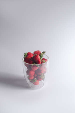 Strawberries in a glass on a white gray background. Strawberry in glass cup on white gray background.の写真素材