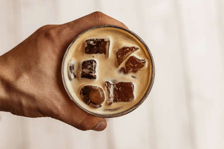 Espresso tonic in hand Espresso tonic in hand on a wooden background trayの写真素材