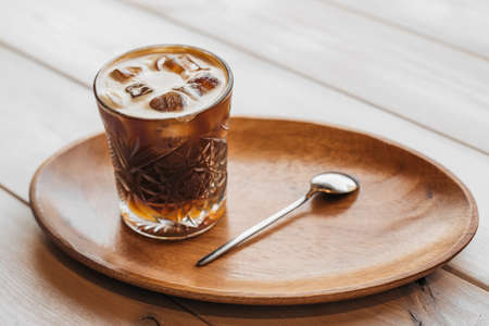 Espresso tonic coffee in a glass in a hand on a wooden background. Espresso tonic cup ice.の写真素材