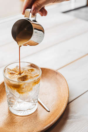 Espresso tonic coffee in a glass in a hand on a wooden background. Espresso tonic cup ice.の写真素材