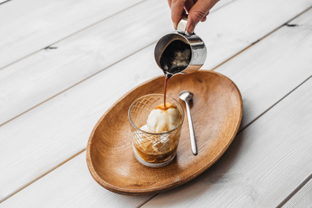 Iced coffee with ice cream in a cup on a table with a tray. Coffee with ice cream on wooden table in cup.の写真素材