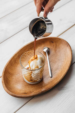 Iced coffee with ice cream in a cup on a wooden table with a tray. Coffee with ice cream on wooden table in cup.の写真素材